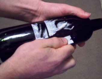 Removing the label from the wine bottle with a sharp knife.